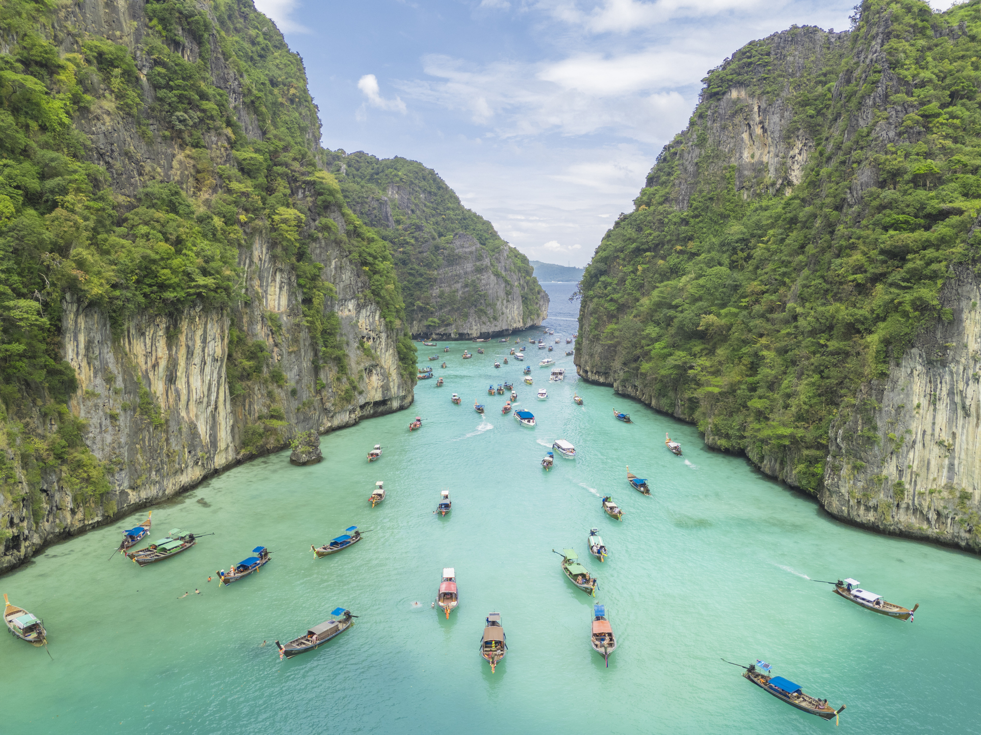 Aerial view of Phi Phi islands Travel Landmark of Krabi Phuket, Thailand. Drone POV fly over Pileh Lagoon with traditional long-tail boats floating on stunning turquoise waters. Maya beach natural popular destination for tourists in summer holidays.