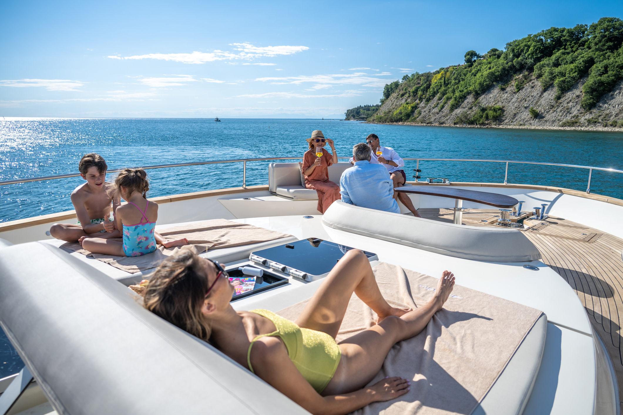 Family relaxing on sofa and sun loungers on luxury yacht.